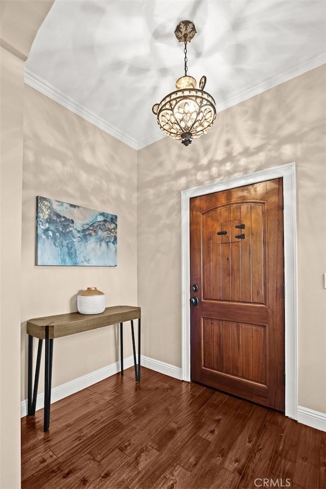 foyer entrance featuring an inviting chandelier, crown molding, baseboards, and dark wood-style flooring