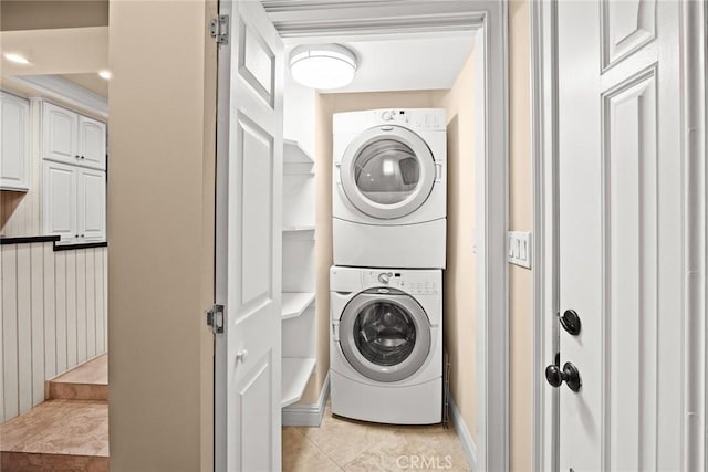 laundry area with light tile patterned floors, stacked washer and clothes dryer, and laundry area