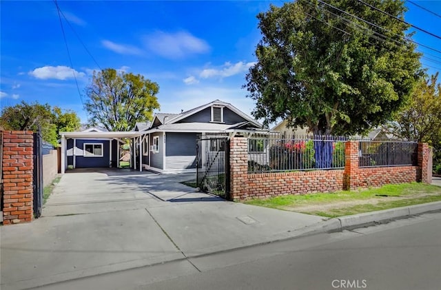 view of front of home with concrete driveway, a carport, and a fenced front yard