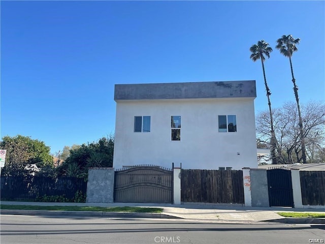 exterior space featuring a gate, a fenced front yard, and stucco siding