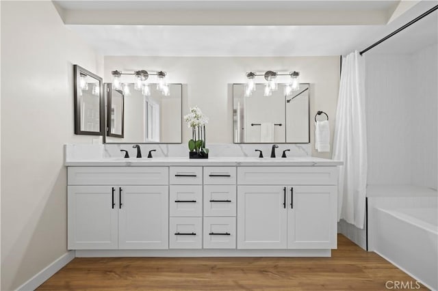 full bath with double vanity, wood finished floors, and a sink