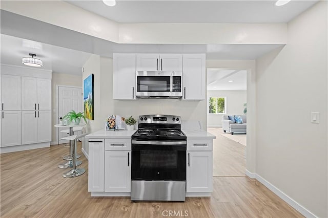 kitchen with light wood-type flooring, white cabinets, stainless steel appliances, and light countertops