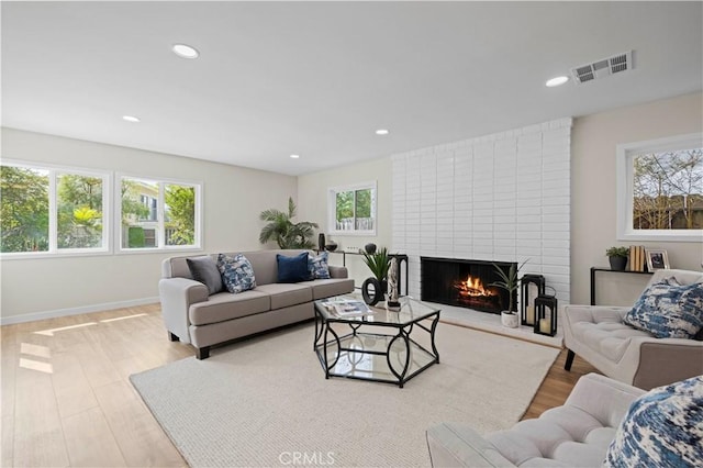 living room featuring wood finished floors, visible vents, baseboards, recessed lighting, and a brick fireplace