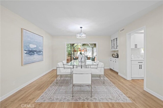 dining room featuring visible vents, baseboards, light wood-style floors, and a notable chandelier