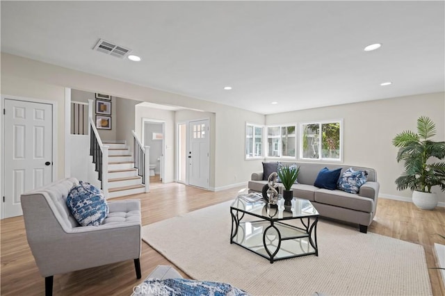 living area featuring recessed lighting, visible vents, light wood-style flooring, and stairway