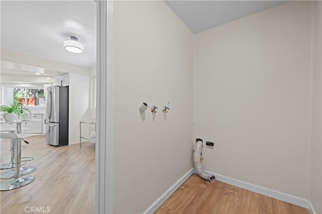 washroom featuring laundry area, light wood-type flooring, and baseboards