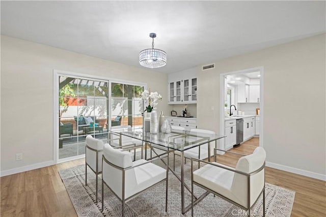 dining area with an inviting chandelier, light wood-style floors, visible vents, and baseboards