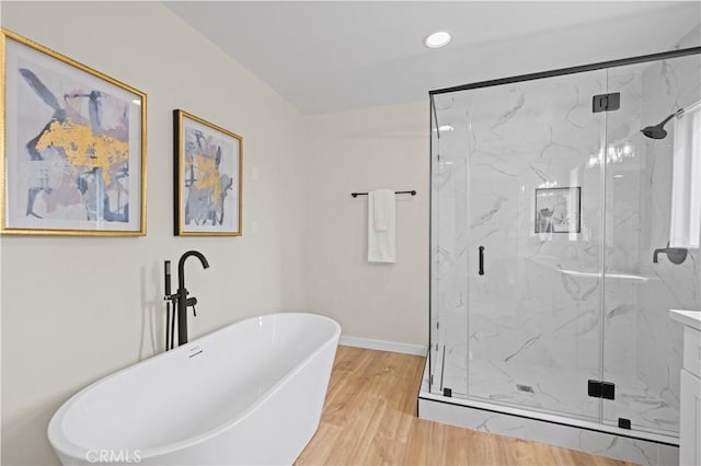 full bath with a freestanding tub, wood finished floors, recessed lighting, a marble finish shower, and baseboards