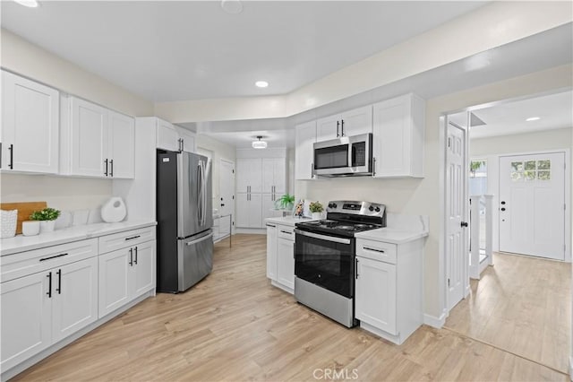 kitchen featuring light wood-style floors, appliances with stainless steel finishes, white cabinets, and light countertops