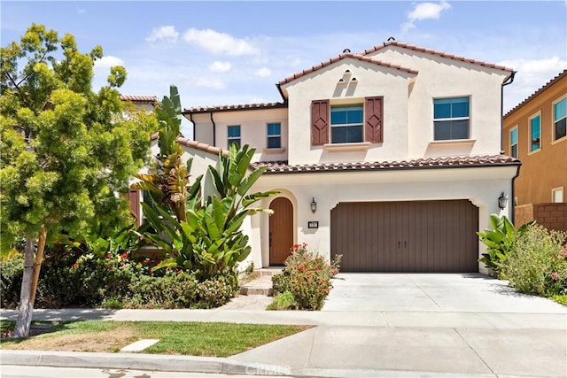 mediterranean / spanish-style home featuring stucco siding, an attached garage, driveway, and a tile roof