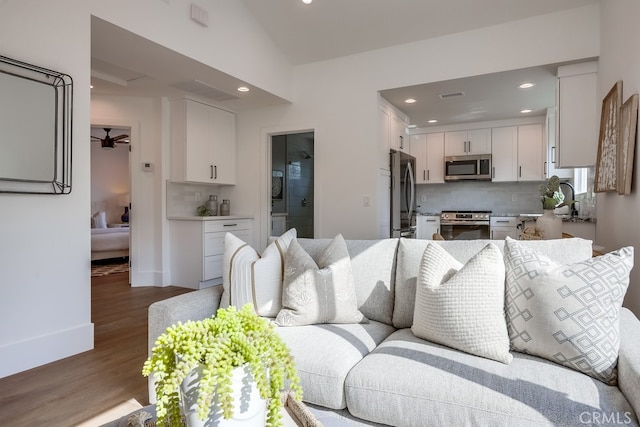 living area with a ceiling fan, recessed lighting, wood finished floors, and visible vents