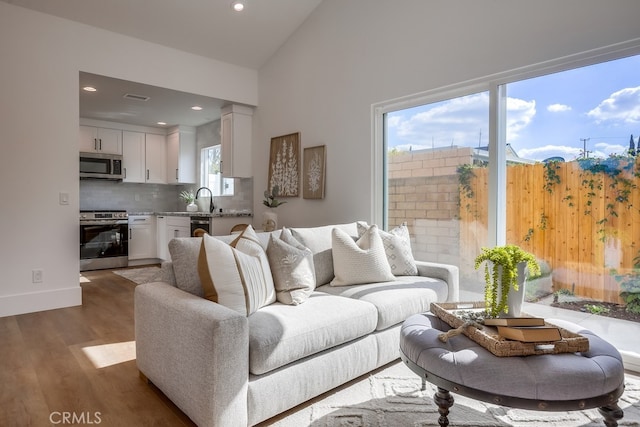 living room featuring dark wood-style floors, baseboards, visible vents, recessed lighting, and vaulted ceiling