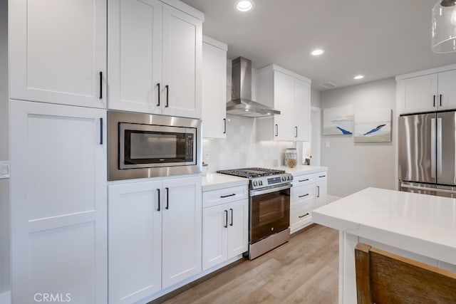 kitchen featuring stainless steel appliances, tasteful backsplash, wall chimney exhaust hood, and white cabinets