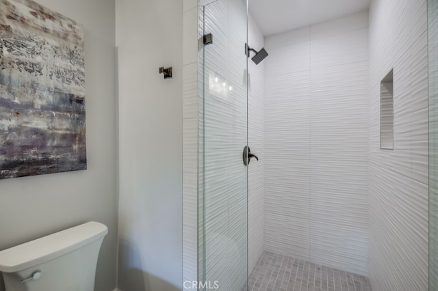 bathroom featuring a tile shower and toilet