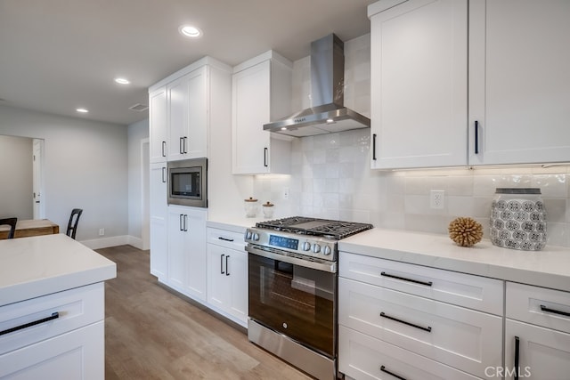 kitchen with backsplash, light wood-type flooring, recessed lighting, stainless steel appliances, and wall chimney exhaust hood