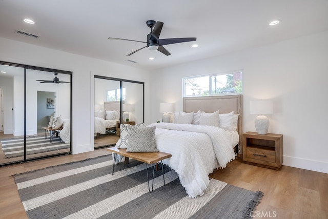 bedroom with recessed lighting, visible vents, two closets, and light wood-style flooring