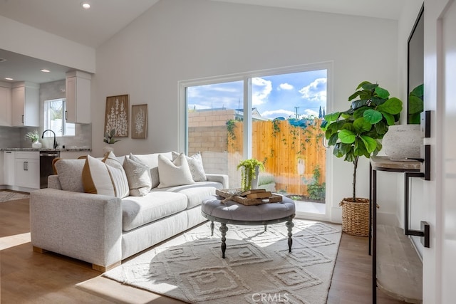 living area featuring recessed lighting, high vaulted ceiling, and light wood finished floors