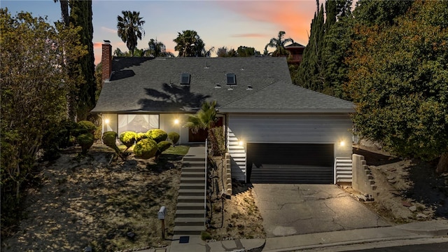 view of front of property with a garage, roof with shingles, and concrete driveway