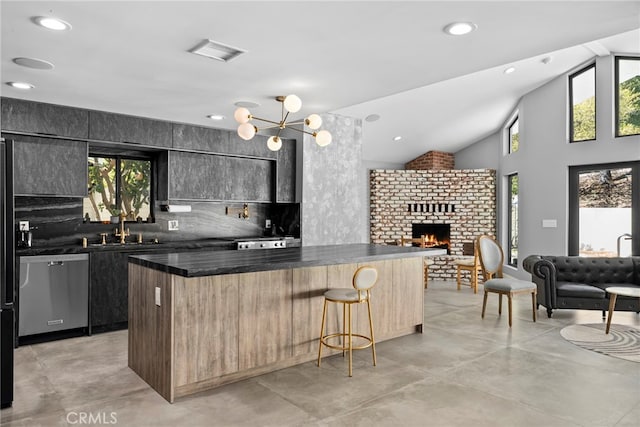 kitchen with dark countertops, a center island, open floor plan, dishwasher, and a sink