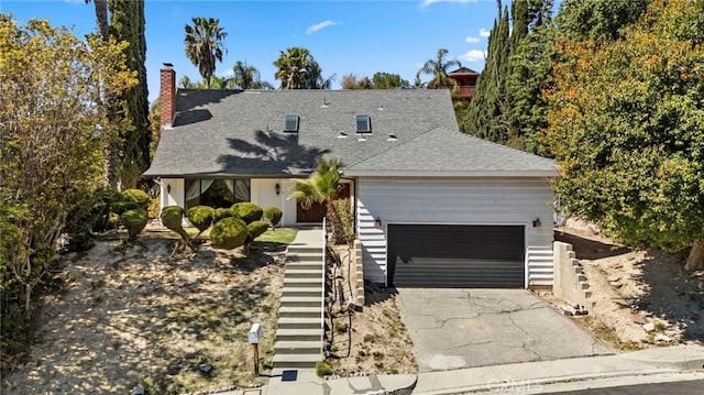 view of front of house with a chimney, driveway, roof with shingles, a garage, and stairs