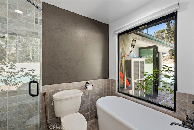 bathroom featuring a soaking tub, toilet, a stall shower, and tile walls