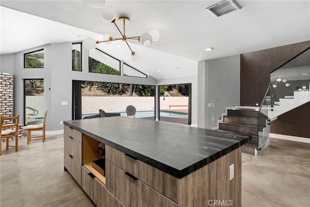 kitchen with dark countertops, visible vents, a center island, high vaulted ceiling, and modern cabinets