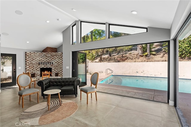 living room featuring a brick fireplace, concrete flooring, and a healthy amount of sunlight