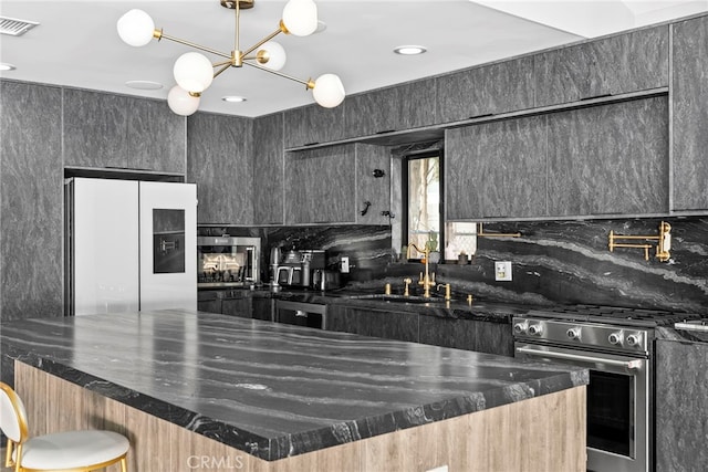 kitchen with visible vents, a large island, white refrigerator with ice dispenser, gas stove, and decorative backsplash