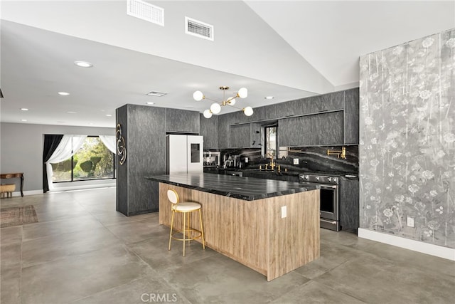 kitchen featuring dark countertops, visible vents, a kitchen island, freestanding refrigerator, and gas stove