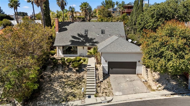 view of front of home featuring driveway, fence, a shingled roof, a garage, and a chimney