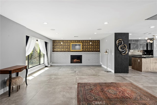 living room featuring a brick fireplace, an accent wall, baseboards, concrete flooring, and recessed lighting