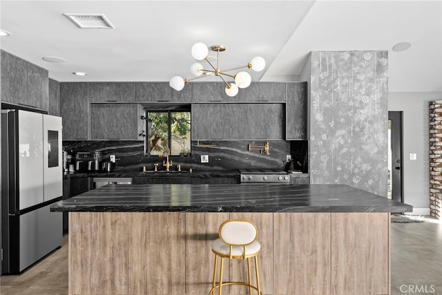 kitchen featuring a breakfast bar area, visible vents, a sink, appliances with stainless steel finishes, and modern cabinets