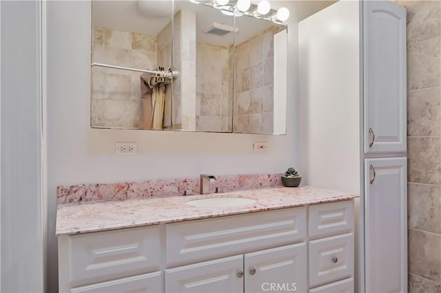 bathroom with tiled shower and vanity