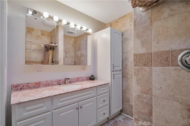 bathroom featuring tiled shower and vanity