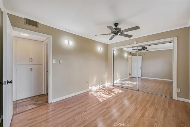 unfurnished bedroom with visible vents, light wood-style flooring, baseboards, and ornamental molding