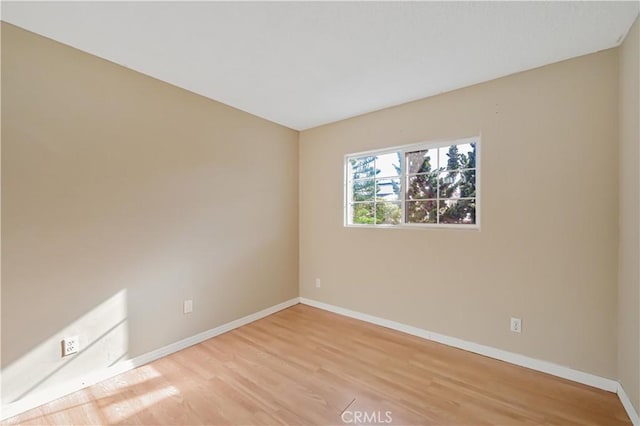 unfurnished room featuring baseboards and light wood-type flooring