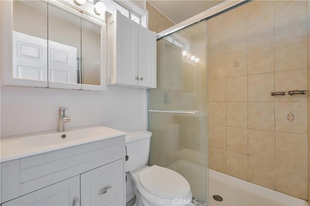 full bath with vanity, a shower stall, and toilet