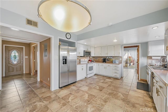 kitchen with visible vents, a sink, white cabinets, appliances with stainless steel finishes, and backsplash