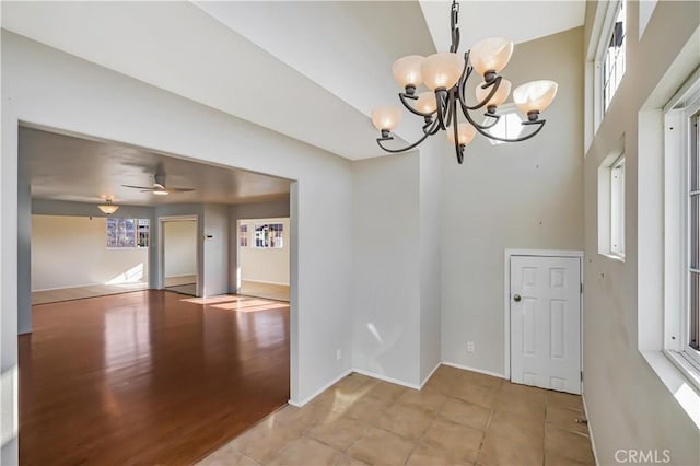 spare room with tile patterned floors, baseboards, a high ceiling, and ceiling fan with notable chandelier