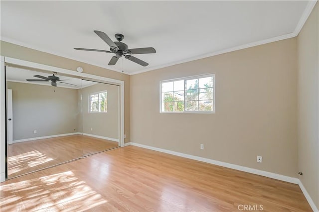 unfurnished bedroom with light wood finished floors, ceiling fan, baseboards, ornamental molding, and a closet