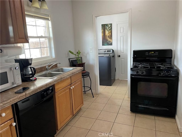 kitchen with light tile patterned floors, black appliances, a sink, and washer / dryer