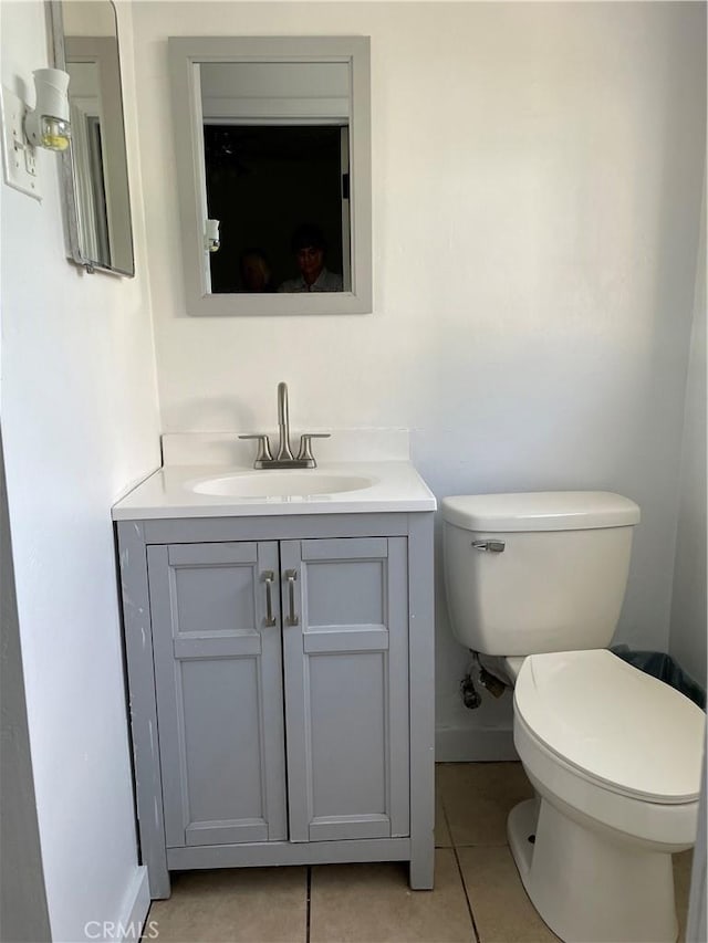 half bath featuring tile patterned floors, toilet, vanity, and baseboards