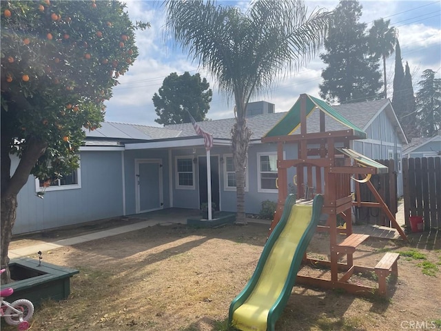 back of house featuring a chimney, a playground, and fence