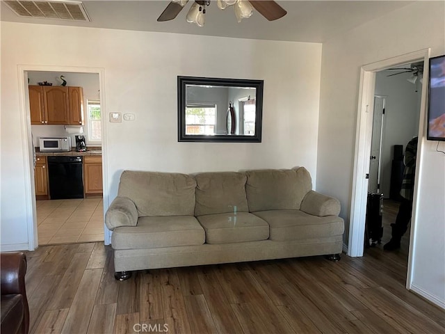 living room with a ceiling fan, visible vents, wood finished floors, and baseboards