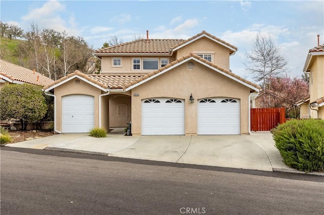 view of front of property with fence, a tiled roof, stucco siding, driveway, and an attached garage