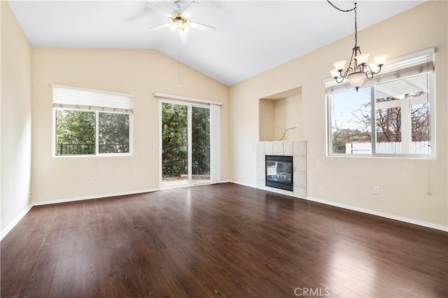 unfurnished living room with baseboards, lofted ceiling, ceiling fan with notable chandelier, a tile fireplace, and wood finished floors