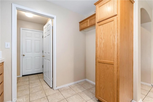 interior space featuring light tile patterned floors, arched walkways, and baseboards