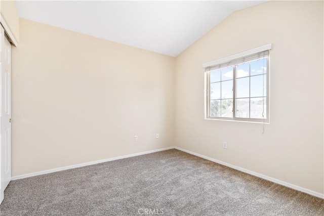 empty room with baseboards, lofted ceiling, and carpet floors