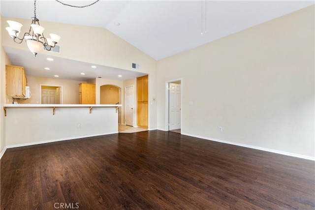 unfurnished living room with an inviting chandelier, wood finished floors, visible vents, and baseboards