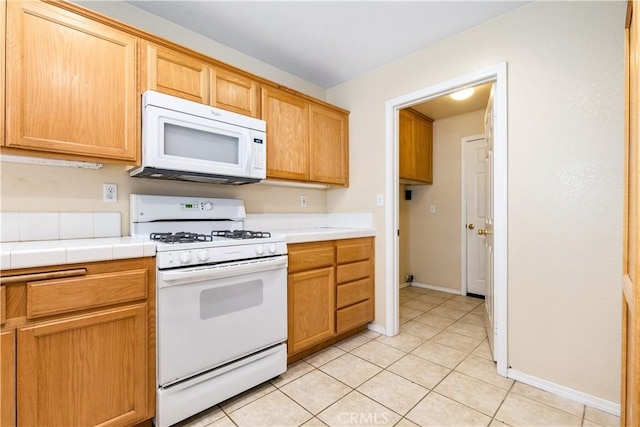 kitchen with tile countertops, baseboards, white appliances, and light tile patterned flooring